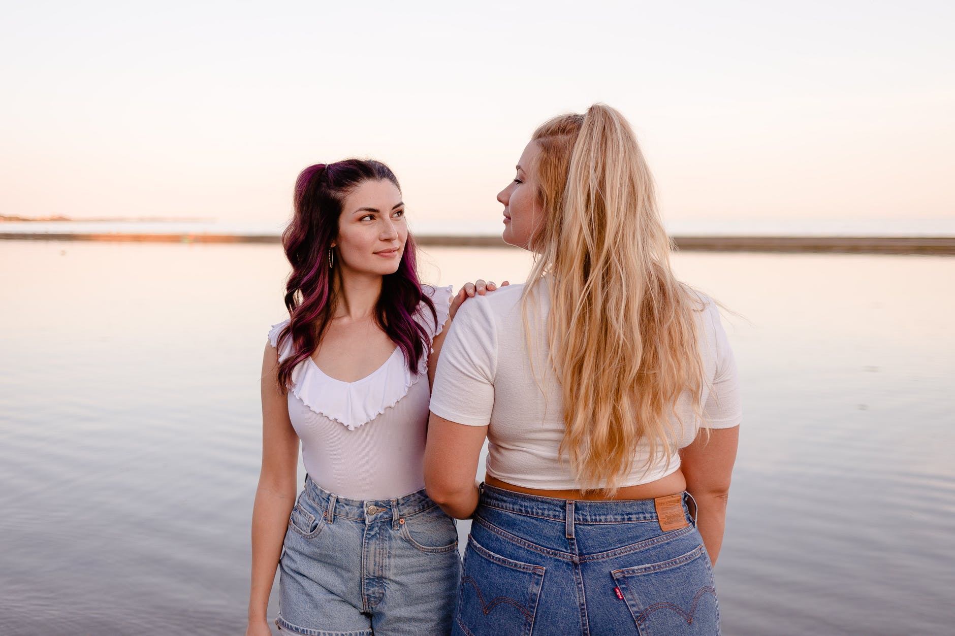 positive females standing on seashore in summer day